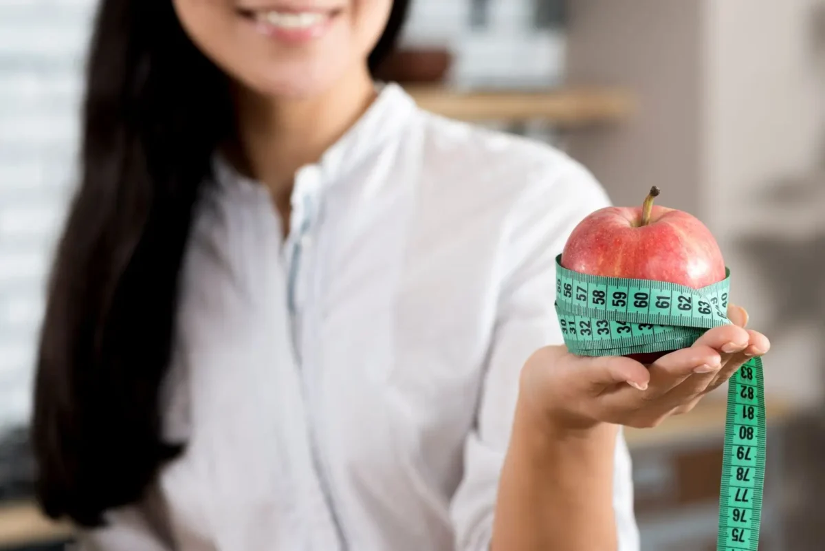 Person holding apple wrapped in measuring tape