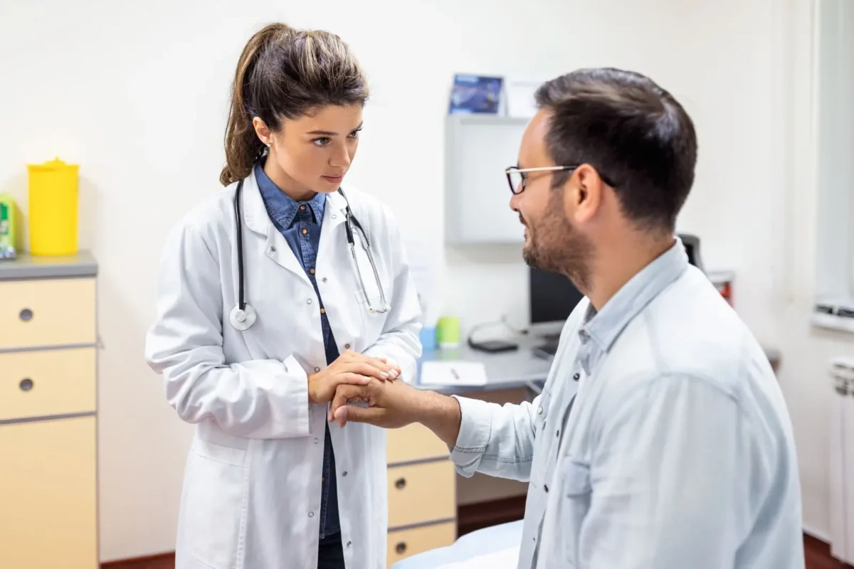 Female doctor examining male patient's hand